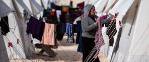 A Syrian refugee woman who fled violence in Syrian city of Ain al-Arab, known also as Kobani, hangs clothes outside her tent in a camp in the border town of Suruc, Turkey, Monday, Feb. 2, 2015. | ASSOCIATED PRESS